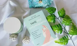 Książka "Twój styl przywiązania" Diane Poole Heller na tle białego materiału, obok ozdobnego pudełka i zielonych liści.