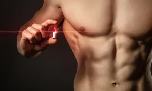 Mężczyzna z wyrzeźbionym torsem trzyma ampułkę, symbolizującą walkę z bigoreksją i dążenie do idealnego ciała.