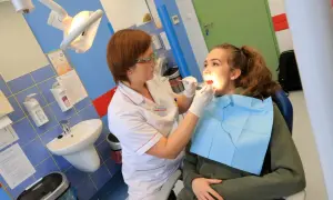 Dentystka bada zęby młodej pacjentki w gabinecie stomatologicznym.