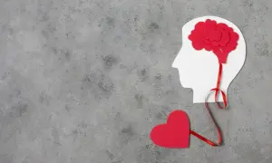 Czerwone serce połączone wstążką z mózgiem w profilu głowy. Symbolizuje to emocjonalne reakcje neurotyka.
