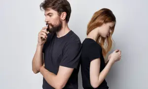 Para stojąca plecami do siebie, oboje patrzą w telefony. On zamyślony, ona zrezygnowana. Cisza między nimi to wyraźny **silent treatment**.