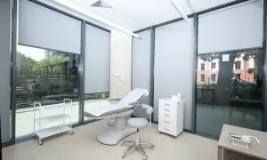 Gabinet dermatologiczny z fotelem zabiegowym, szafką i wózkiem.