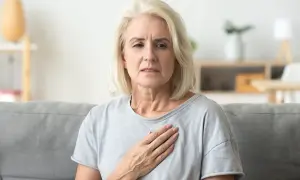 Kobieta z ręką na piersi, szukająca sposobów, jak pokonać duszności w nerwicy.