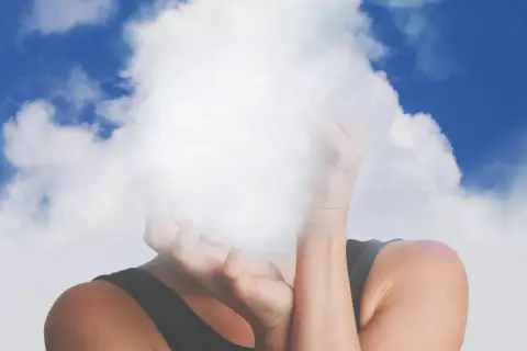 Osoba z twarzą ukrytą w chmurach, symbolizującą mgłę mózgową.
