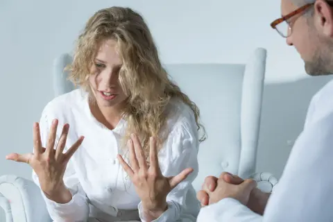 Kobieta z burzą blond włosów opowiada o swoich przeżyciach podczas terapii. Leczenie schizofrenii wymaga wsparcia.