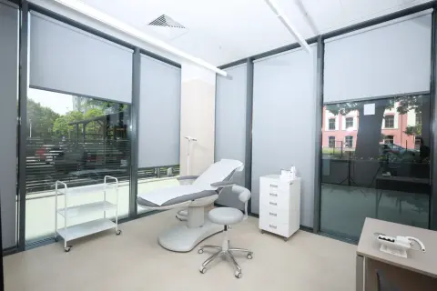 Gabinet dermatologiczny z fotelem zabiegowym, szafką i wózkiem.