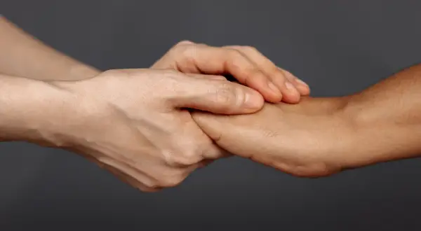 Dwie dłonie splatają się, symbolizując wsparcie i nadzieję dla psychiki mężczyzny po rozwodzie.