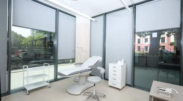 Gabinet dermatologiczny z fotelem zabiegowym, szafką i wózkiem.