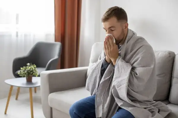 Mężczyzna okryty kocem, z chusteczką przy nosie, może sugerować objawy choroby, ale czasem to tylko próba zwrócenia na siebie uwagi, jak w przypadku zespołu Munchausena.