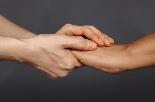 Dwie dłonie splatają się, symbolizując wsparcie i nadzieję dla psychiki mężczyzny po rozwodzie.